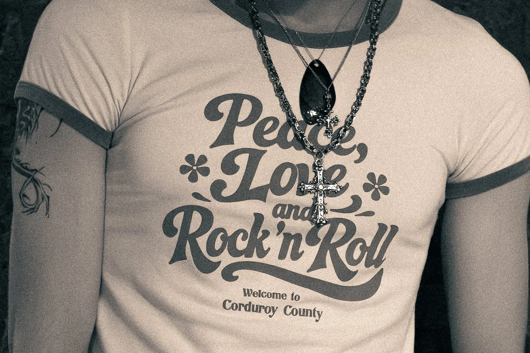 Close-up of the ringer T-shirt worn under layered chains and a cross pendant.