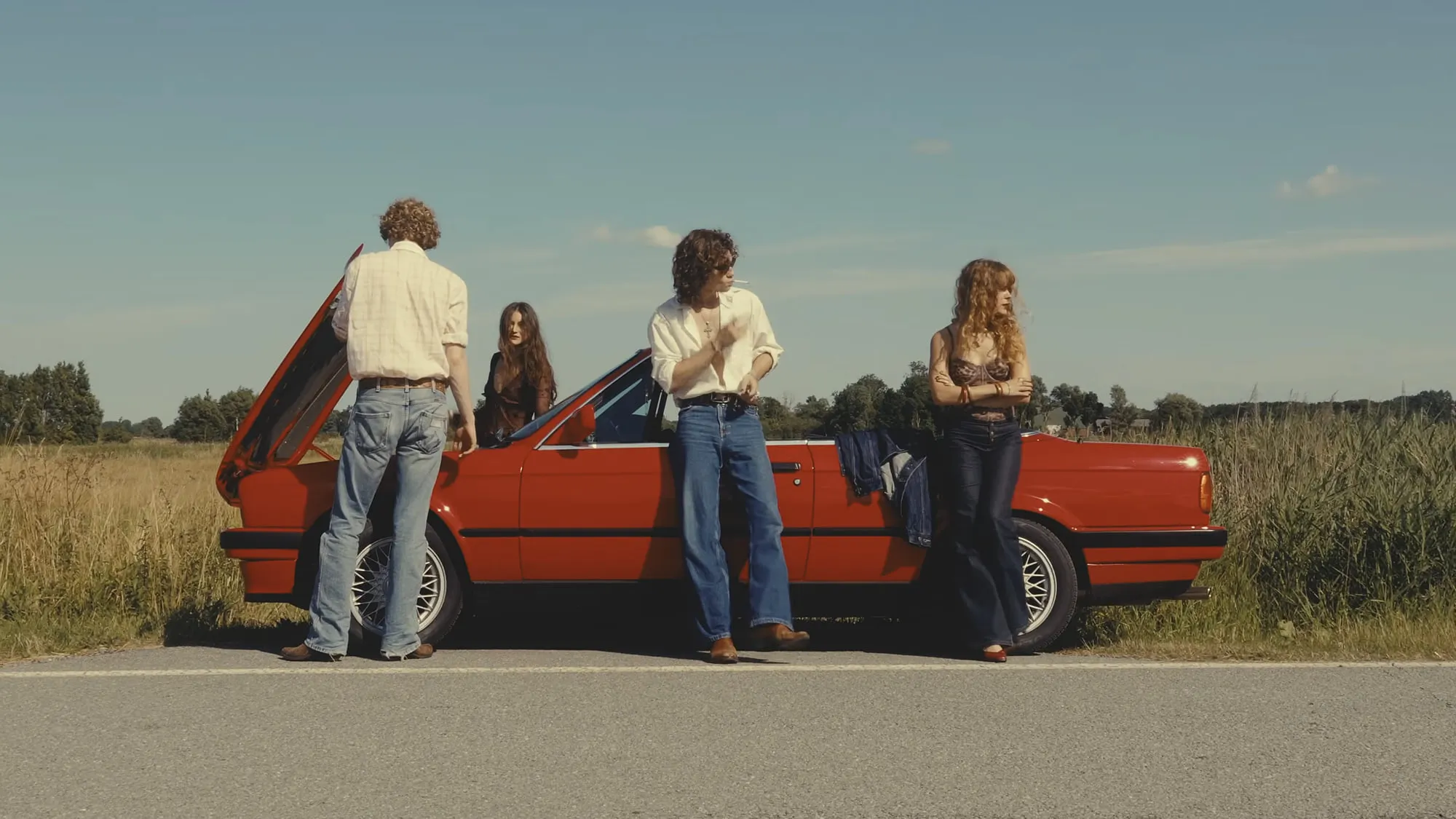Cover of “Summer ’23”: the four members of Corduroy County standing around a red convertible parked on a country road under a wide summer sky.